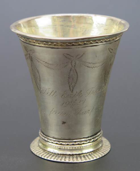 Bägare, silver, 1700-talets mitt, svagt konisk på låg fotklack, stämplad Martin Bernström Härnösand före 1755 (verksam 1742-79), h 7 cm, vikt 65 gram, senare gåvogravyr, spricka i fotklack