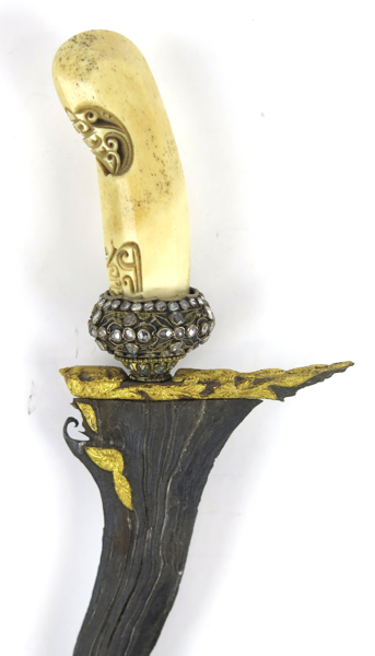 Dolk i balja, så kallad Keris (Kris), Malaysia, 18-1900-tal, sjuvågig, delvis förgylld damaskerad klinga, sammansatt fäste med parerring helt besatt med delvis obearbetade vita safirer,