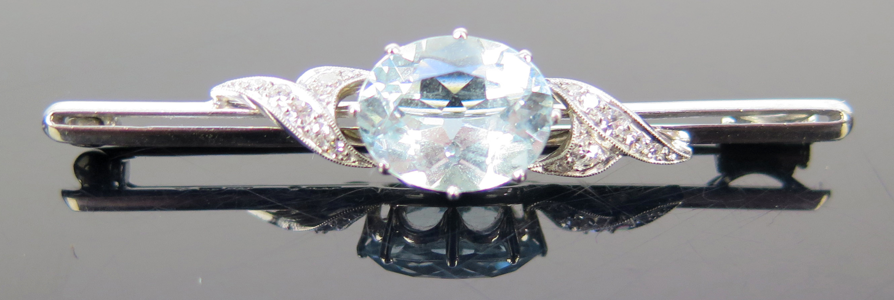 Brosch, 18 karat vitguld med 1 facettslipad akvamarin om cirka 5 carat samt 14 8-slipade diamanter om totalt 0,22 carat, l 55mm, vikt 6,2 gram, stämplad C G Hallberg Stockholm 1952