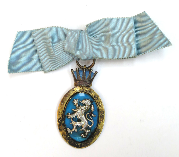 Medalj, delvis förgyllt silver och emalj, dekor av Hallands Landskapsvapen under hertigkrona, original serafimerblå rosett, 40 x 25 mm, stämplad Stockholm 1904