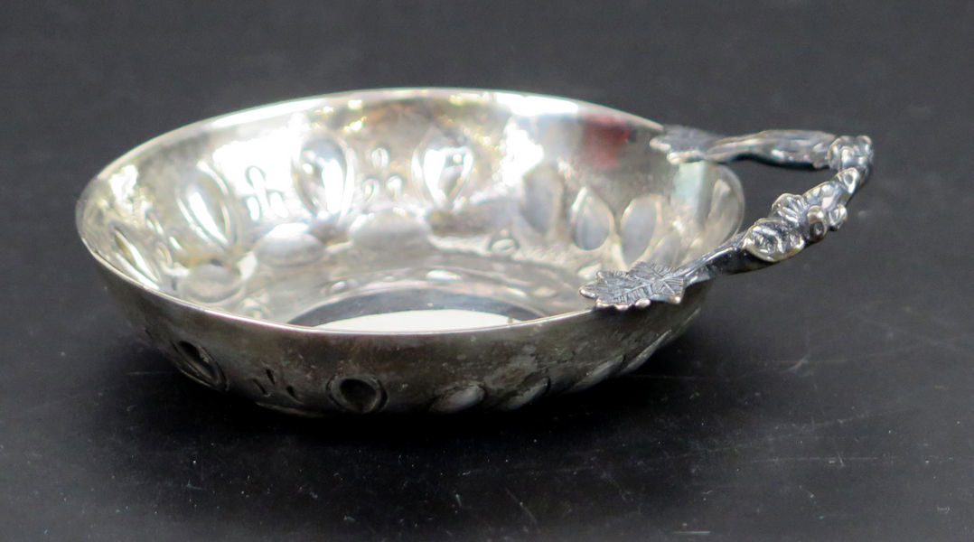 Tastevin, silver, rund med hänkel i form av vinranka, stämplad Gösta Wessfelt Malmö, dia 7,5 cm, vikt 55 gram